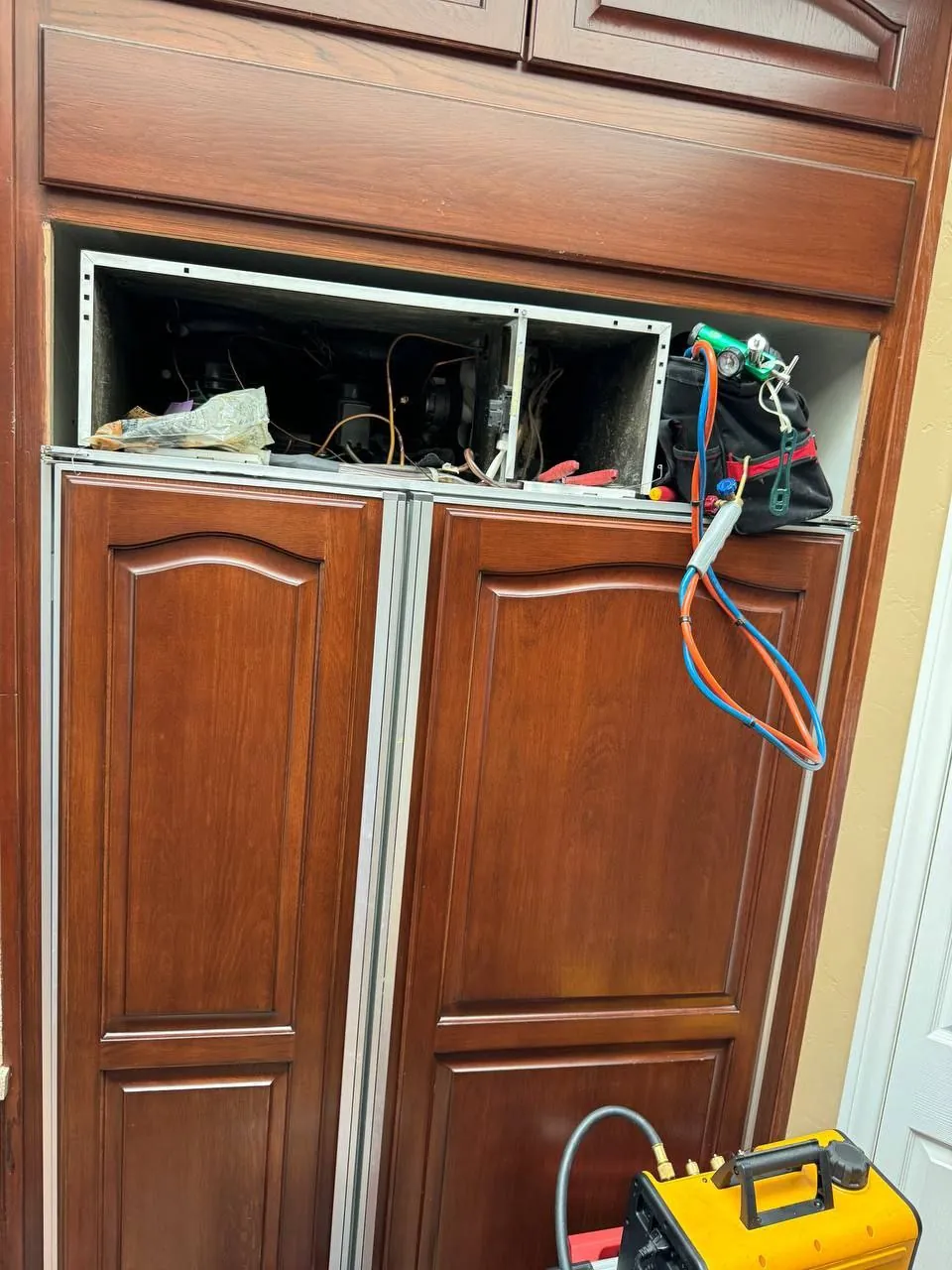 Wood-panel Sub-Zero built-in open at the top for service